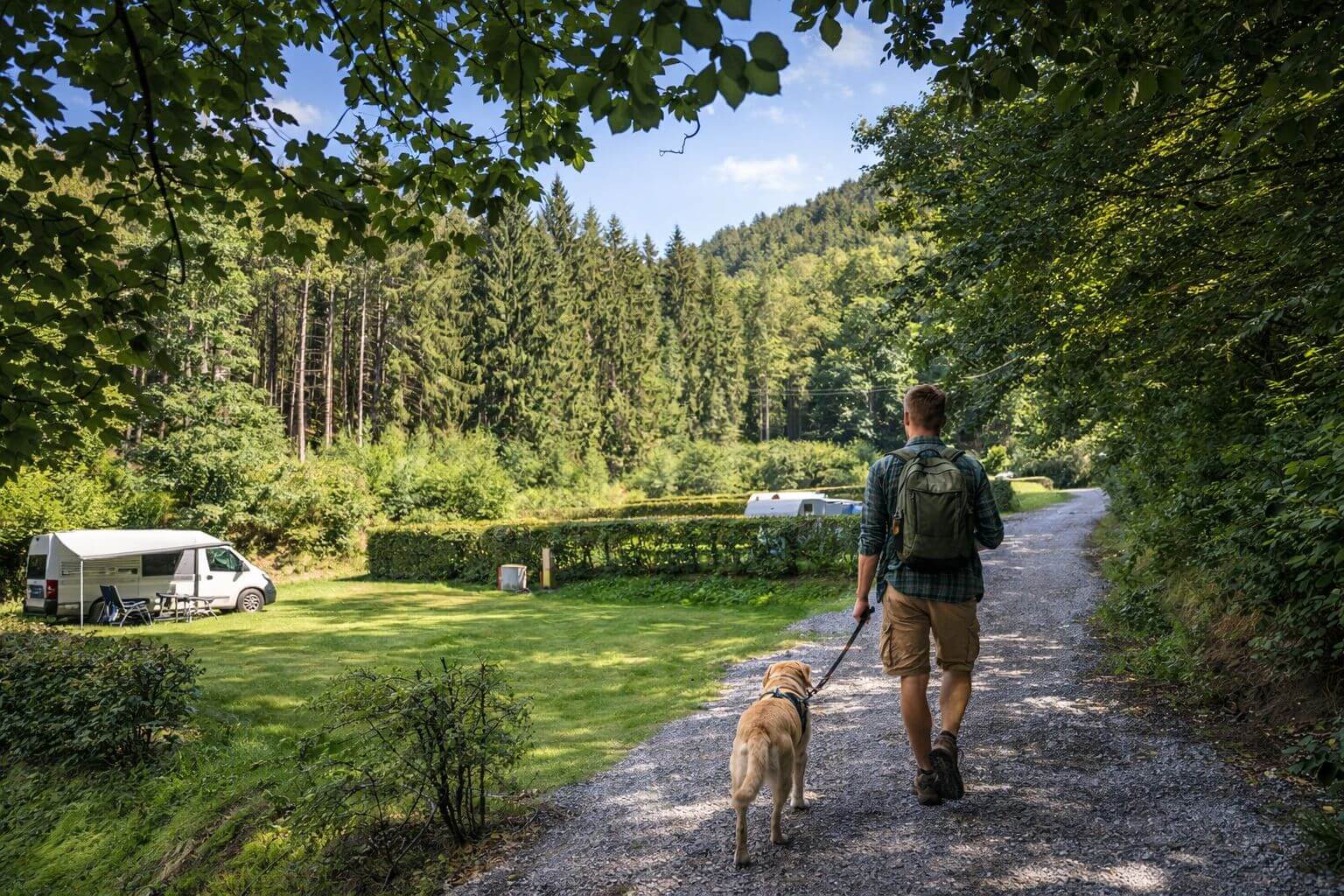Camping mit Hund - Mann mit Hund auf dem Campingplatz